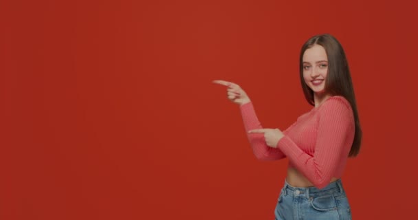 Hermosa chica sonriente apuntando al espacio de copia a un lado, mostrando maqueta de espacio de trabajo para publicidad, contenido promocional — Vídeos de Stock