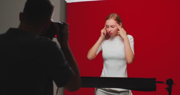 Bakom kulisserna på fotoshoot, bakom scenen. Vacker kvinnlig modell poserar i studio, fotograf tar bilder — Stockvideo