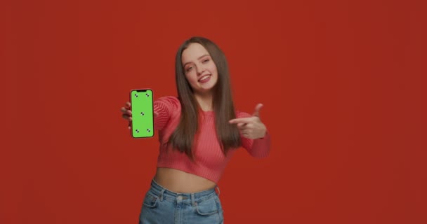 Muchacha joven moderna mostrar el teléfono señalando con el dedo en la pantalla verde croma plantilla clave, anunciar aplicaciones modernas — Vídeos de Stock