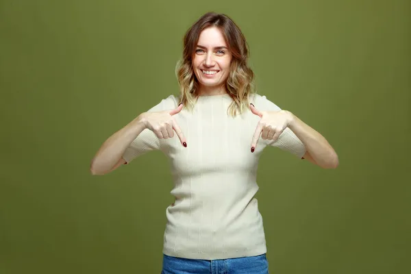 Boldog fiatal nő ujjal mutogatva alatt jelzi eladási ajánlat, mosolygós lány reklám, pont le a zöld háttér — Stock Fotó