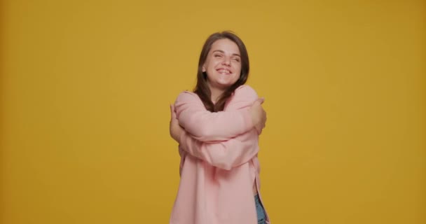 年轻而快乐的漂亮姑娘在黄色的背景下充满自信地拥抱着自己 自我照顾 身体积极的观念 高质量的4K镜头 — 图库视频影像