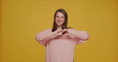 Gülümseyen genç kız göğsüne yakın bir kalp hareketi gösteriyor. Gönüllü genç bayan yardım ve bağışta bulunun.