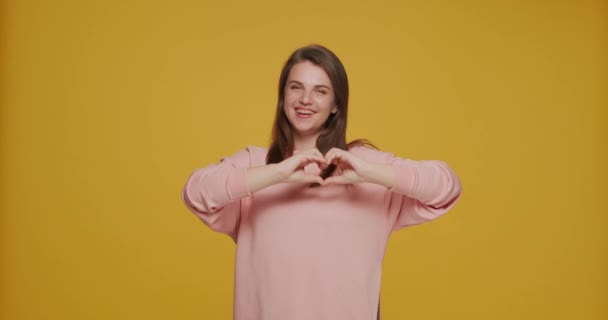 Une jeune fille souriante montre un geste de cœur tendre près de la poitrine. Une jeune bénévole demande à soutenir des organismes de bienfaisance, des dons — Video