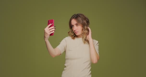 Όμορφη νεαρή κοπέλα ποζάρουν, λαμβάνοντας selfie στο τηλέφωνο για το περιεχόμενο του blog κοινωνικό δίκτυο σε φυσικό πράσινο φόντο στούντιο — Αρχείο Βίντεο