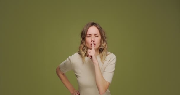 Shh, sprich nicht. Ernstes Mädchen zeigt Schweigegeste, bittet zu schweigen, hält Geheimnis auf grünem Studiohintergrund — Stockvideo