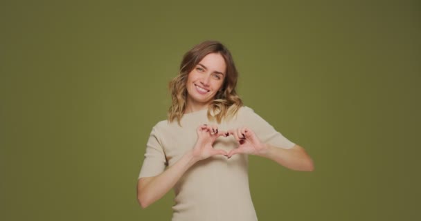 Hermosa mujer haciendo gesto en forma de corazón en el pecho, besos de golpe. Emoción positiva, amor, caridad, concepto de donación — Vídeo de stock