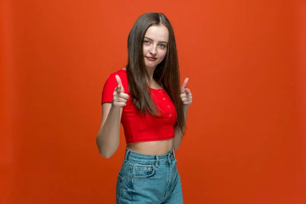 Oye, tú. Joven hermosa chica apuntando a la cámara con los dedos sobre fondo naranja con espacio de copia para la publicidad —  Fotos de Stock