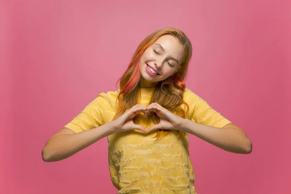 Leende vänlig ung flicka frivillig göra hjärta gest, kärlek tecken. Välgörenhet, donation, begreppet goda gärningar — Stockfoto