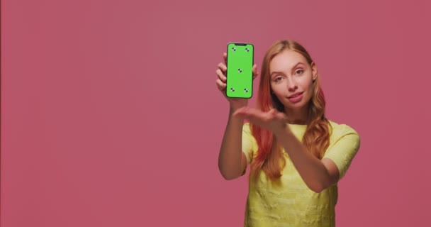 Menina bonita mostrando telefone com tela verde modelo de chave chroma recomendar aplicação. Copyspace para anunciar — Vídeo de Stock