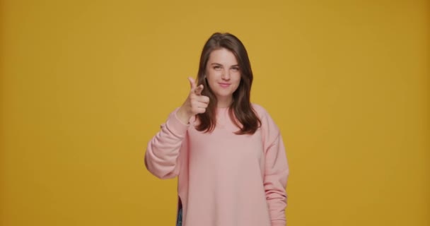 Hey you, choice gesture. Pretty young caucasian girl pointing at camera by fingers, picks candidate on yellow background — Stock Video