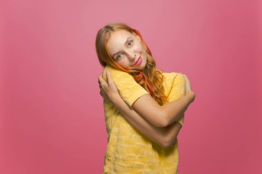 Pembe arka planda zevkten gülümseyen güzel bir genç kız. Öz-sevgi, pozitif özsaygı kavramı