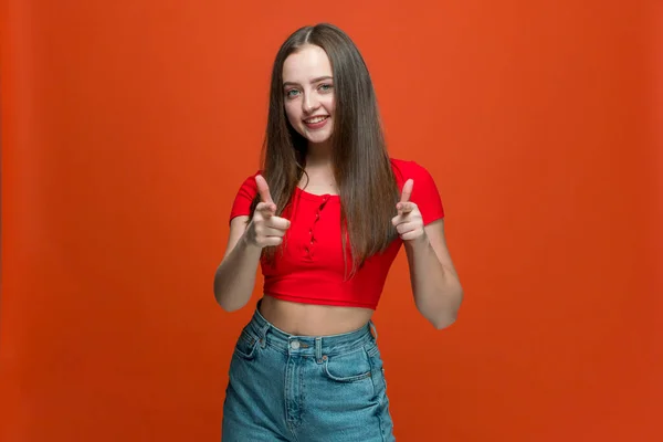 Megvagy. Magabiztos fiatal lány mosolyog mutató kamera ujjaival, választott meg a narancs stúdió háttér — Stock Fotó