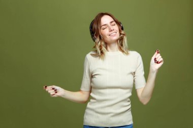 Mutlu, sakin, kulaklık takan, modern müzik dinleyen, gülümseyen genç bir kız.