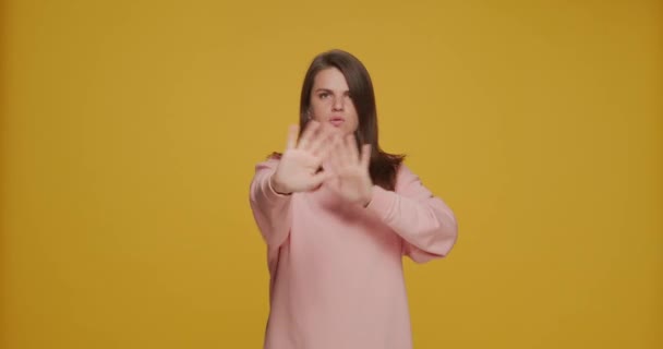 Jeune fille mécontente arrêter geste, nier la mauvaise offre, dire non, rejeter, refuser suggestion sur fond jaune studio — Video