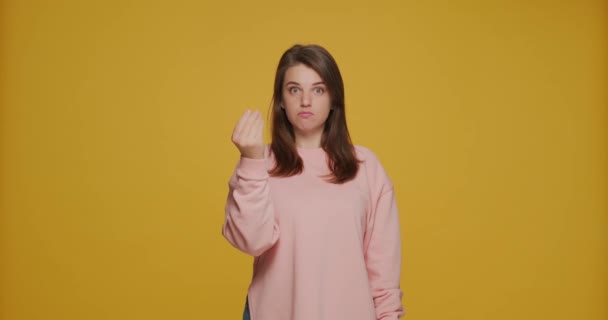 Daj gotówkę. Dość młoda zabawna dziewczyna robi gest pieniędzy, prosząc o zapłatę, dodatek na żółtym tle studio — Wideo stockowe
