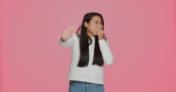 Bau busuk. Gadis Asia muda mencubit hidung untuk menahan napas, merasa jijik dengan bau yang tidak menyenangkan di latar belakang studio merah muda — Stok Video