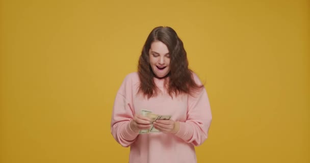 Recompensas financeiras, fortuna. Menina feliz contando notas de dólar regozijando grande dinheiro, jackpot no fundo amarelo — Vídeo de Stock