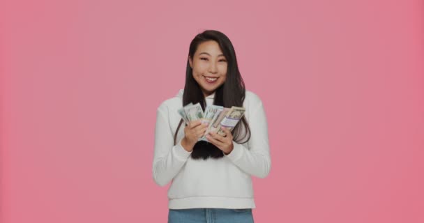 Большой джекпот. Богатая молодая азиатская девушка с долларовыми банкнотами выигрывает улыбаясь, довольствуясь денежными вкладами, финансовыми сбережениями — стоковое видео