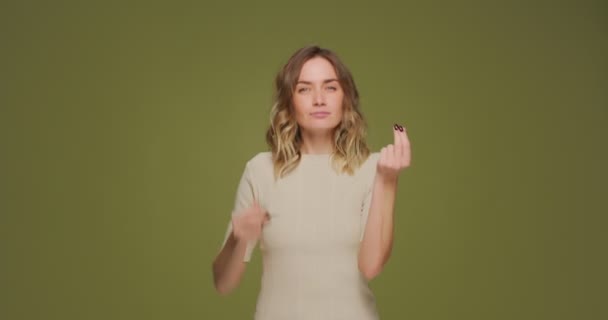 Ung vakker kvinne viser pengegebyr med fingre, ber om gjeld, lønn eller honorar på grønn studiobakgrunn – stockvideo