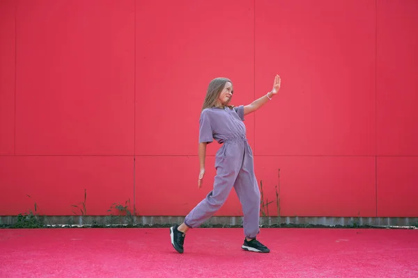 Chica adolescente activa bailando al aire libre sobre fondo rojo de la pared. Elegante joven bailarina moderna realiza danza contemporánea de hip hop —  Fotos de Stock