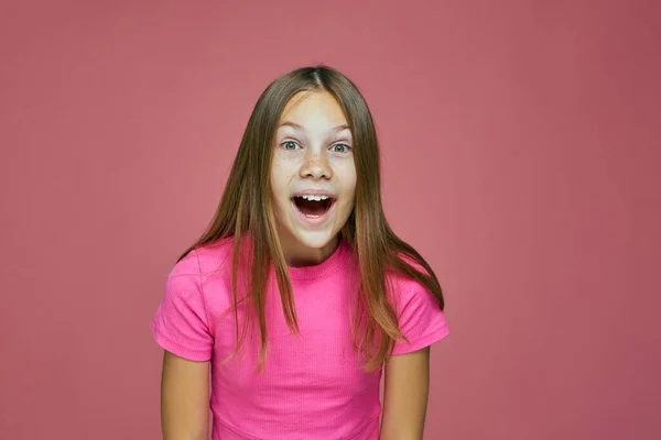 Aranyos érzelmi kislány gyermek meglepett nézi kamera érzés csodálkozik, csodálkozik, csodálkozik a rózsaszín háttér — Stock Fotó