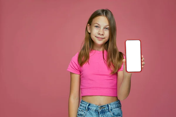 Feliz niña emocionada mostrar teléfono con pantalla en blanco maqueta sobre fondo rosa, anunciar nuevas aplicaciones móviles — Foto de Stock