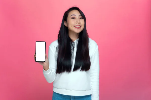 Sorridente ragazza asiatica che mostra il telefono con lo schermo mock up vuoto che presenta nuove applicazioni mobili, servizi pubblicitari — Foto Stock