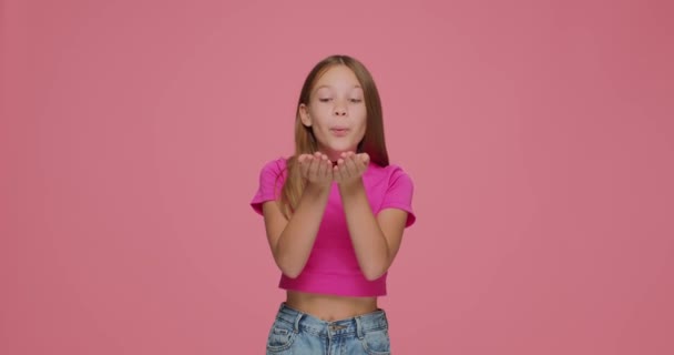 Щаслива маленька дівчинка дитина дме блискітки конфетті з долонь, веселячись святкуючи день народження на рожевому фоні — стокове відео