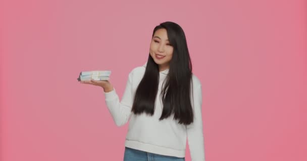 Sorte jovem asiático menina segurar pilha de dinheiro, apontando para o dólar em dinheiro na mão, desfrutando de vitória, jackpot no fundo do estúdio rosa — Vídeo de Stock
