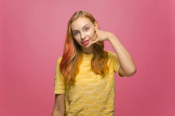 Gyönyörű modern fiatal kaukázusi lány bemutató hívjon gesztus ujjaival nézi kamera rózsaszín stúdió háttér — Stock Fotó