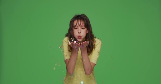 Счастливая молодая красивая девушка празднуют праздник, удар конфетти блестки из пальм, поздравить с хромаки зеленый фон — стоковое видео