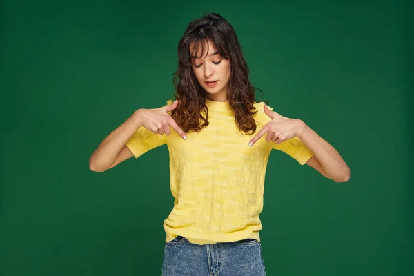 Modern gyönyörű fiatal lány mutat le ujjait a linkre feliratkozni zöld stúdió háttér. Jó eladási ajánlat. — Stock Fotó
