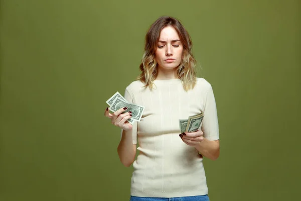 Finanční problém. frustrovaná mladá žena počítání hotovosti dolarové bankovky potřebují peníze na zaplacení dluhu na zeleném pozadí — Stock fotografie