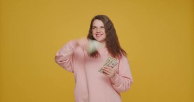 Mutlu zengin genç kız para saçıyor, sarı arka planda zenginliğin tadını çıkarıyor. Piyango, online kumarhane, bahis reklamı.