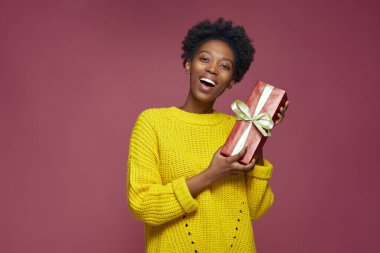 Aşırı neşeli Afrikalı Amerikalı genç kız elinde hediye kutusu, doğum günü hediyesi. Xmas indirimi ve tatil yardım konsepti 