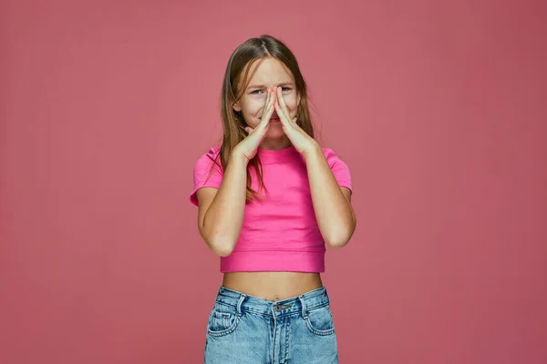 Qué mal olor. Linda niña avergonzada cubrir la cara con las manos defendiendo de hedor repugnante en el fondo del estudio rosa —  Fotos de Stock