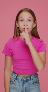 Sessiz olun. Modern genç kız pembe arka planda sessiz jest yapıyor, sosyal ağ için dikey video çekiyor.