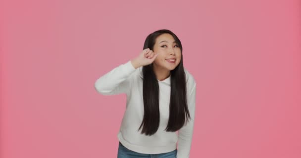 Schweigegegeste. Niedliche moderne asiatische junge Mädchen zeigen stille Zeichen Versprechen geheim zu halten auf rosa Studiohintergrund — Stockvideo