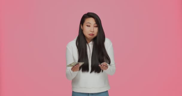 Smutný naštvaný mladý asijské dívka počítat peníze, zdůraznil o finanční problém, dluh nebo bankrot na růžové pozadí studia — Stock video