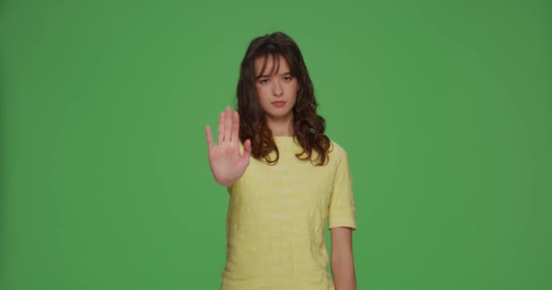 Serieus jong meisje tonen stop gebaar, protesteren, ontkennen, waarschuwen, verbieden op chroma sleutel groene studio achtergrond — Stockvideo