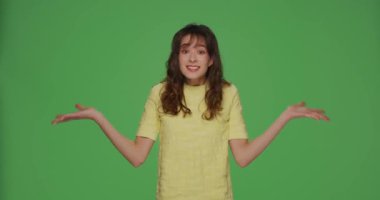 Krom anahtar yeşil arka planda şok ve yanlış anlama hissederek, ellerini açıp, ne soran öfkeli genç kız.