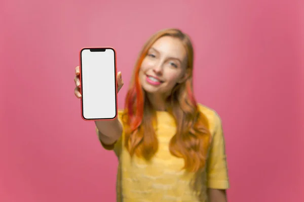 Chica joven feliz mostrando teléfono inteligente con pantalla en blanco simulada vacía para el anuncio móvil, servicios web de publicidad. Primer plano — Foto de Stock