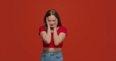 Yüzünde facepalm jesti olan üzgün genç bir kız. Başarısızlık, hata ya da turuncu arka plandaki kötü hafıza yüzünden utanç duyuyor.