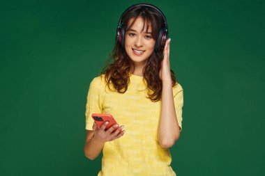 Mutlu genç kız, modern kablosuz kulaklıklarla telefonun tadını çıkararak müzik dinliyor. Müzik uygulamaları reklamcılığı