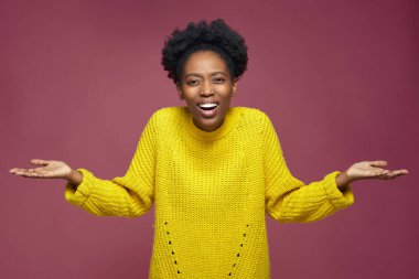 Şaşırmış, mutlu, Afro-Amerikalı genç bir kız ağzı açık, şok olmuş, elleri pembe stüdyo geçmişine yayılmış.