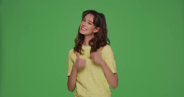 Jolie jolie jeune fille montrant pouces levés, satisfait recommander le service, demander à mettre aime sur fond vert chromakey — Video