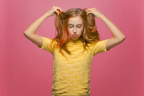 Vacker ung flicka ruffel långa färgade hår slutna ögon njuter styling, perfekt hår skick på rosa bakgrund — Stockfoto