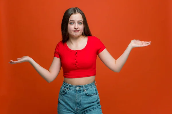 Doubtful puzzled young girl shrugging shoulders, unsure about difficult choice, dont know answer on orange background — Stock Photo, Image