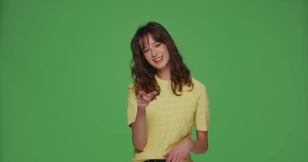 Sorrindo jovem menina moderna apontar para a câmera por dedos, escolhendo o vencedor no fundo verde cromado. Ei, seu gesto. — Vídeo de Stock