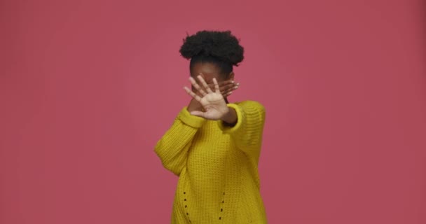Sluta, jag vill inte se det. Rädd ung afrikansk amerikansk kvinna täcka ansikte, visar stopp gest på rosa bakgrund — Stockvideo